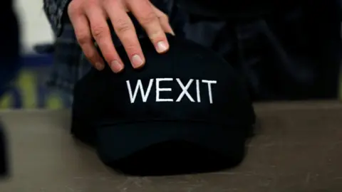 Reuters A supporter holds his Wexit hat while attending a rally for a separatist group seeking federal party status