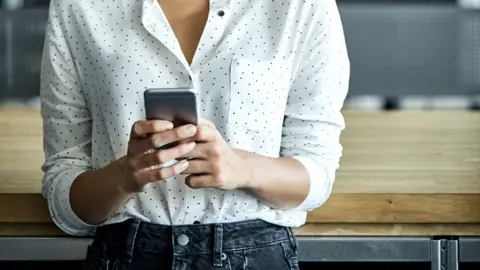 Getty Images A stock image of a woman looking at a mobile phone