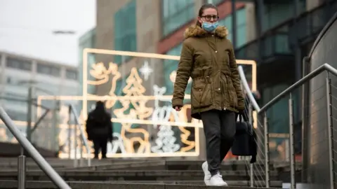 PA Media A person walks amongst festive lighting by the Bullring shopping centre in Birmingham