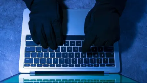 Getty Images Stock photo of gloved hacker using computer