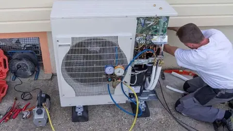 Alamy A man working on a heat pump