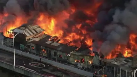 Building engulfed by fire, with thick smoking billowing into the air