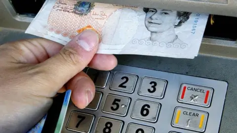 PA Media A person using a cashpoint