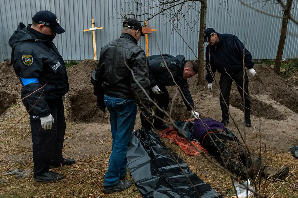 BBC Police in Bucha examine a body unearthed in a field. At least 500 dead have been found since the Russians left.