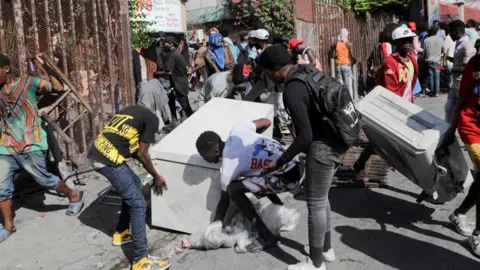 Reuters People steal a fridge from a hotel during a protest demanding the resignation of Haiti's Prime Minister Ariel Henry after weeks of shortages, in Port-au-Prince, Haiti October 10, 2022.