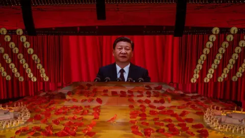 Getty Images Chinese President and Chairman of the Communist Party Xi Jinping appears on a large screen as performers dance during a mass gala marking the 100th anniversary of the Communist Party on 28 June 2021.