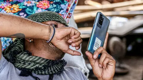 Getty Images A member of the opposition uses his smartphone at base camp