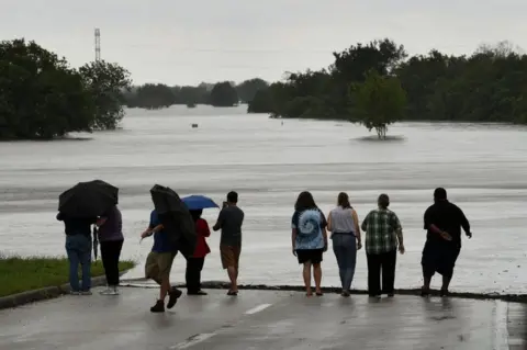 AFP Local residents check the water level of the Barker Reservoir after the Army Corp of Engineers started to release water into the Clodine district as Hurricane Harvey caused heavy flooding in Houston, Texas on 29 August 2017.