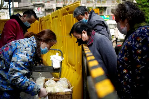 Reuters Residents wearing face masks pay for noodles