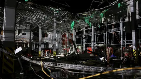 Reuters Police officers inspect a postal distribution centre of Nova Post company hit by Russian missiles, amid Russia's attack on Ukraine, in the village of Korotych, outside of Kharkiv