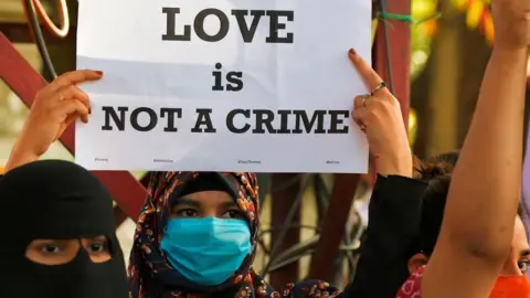 Getty Images A civil right activist holds a placard during a demonstration condemning the decision of various Bharatiya Janata Party (BJP) led state governments in the country for the proposed passing of laws against "Love Jihad" in Bangalore on December 1, 2020.
