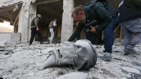 VAHRAM BAGHDASARYAN /PHOTOLURE A photographer at the site of a damaged medical centre after alleged Azerbaijani shelling in Stepanakert in Nagorno-Karabakh, 28 October 2020