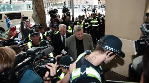 EPA Cardinal George Pell walks into court surrounded by police, media and onlookers
