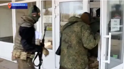 Rodnoi Krasnodon A screenshot from a Russian TV report showing armed men in military clothing entering the television station