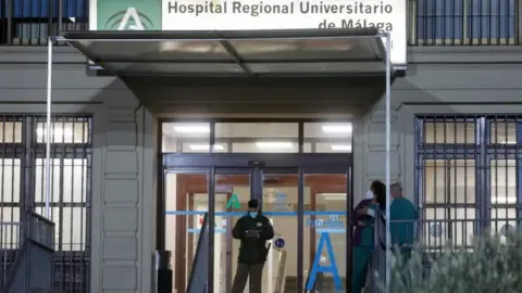 Reuters Healthcare workers stand at the front entrance of the Malaga Regional University Hospital