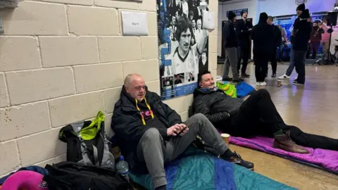 Vaughn Williams Two men sitting on sleeping bags for the charity sleepout event