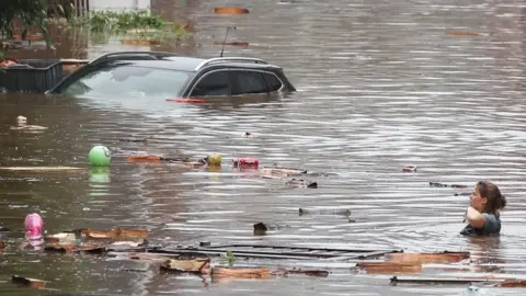 AFP A woman is trying to move in a flooded street following heavy rains in Liege