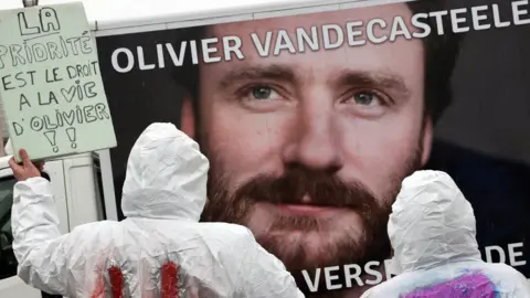 AFP Protesters hold a placard reading "The priority is the right of living for Olivier" during a rally in solidarity with Olivier Vandecasteele in Brussels, Belgium, on 25 December 2022