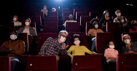 Getty Images Stock image of people watching a performance while wearing facemasks