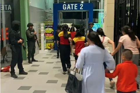 AFP/THAI ROYAL POLICE Security forces evacuate people from the shopping complex