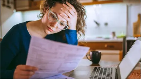 Getty Images Woman at desk with bill