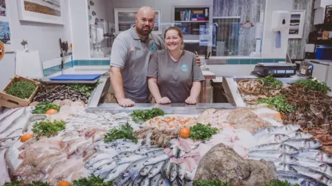 Seafood Cornwall Man and woman in fishmongers with display of fish