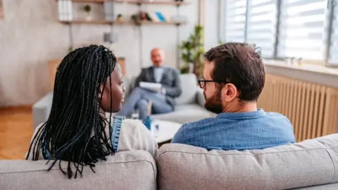 A couple sitting on a couch during a talking session with another person