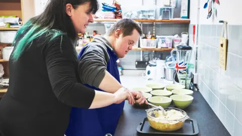 Getty Images/Dean Mitchell Caregiver teaching Down's syndrome student in a kitchen (stock photo)