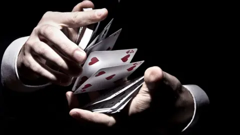 Christopher Grigat/Getty Magician performs card trick