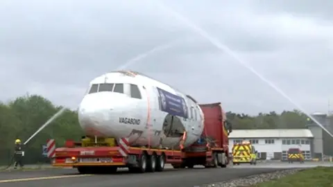 Vickers Viking aircraft fuselage on a lorry trailer passing under water jets