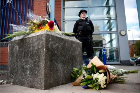 Getty Images police officer standing near flowers