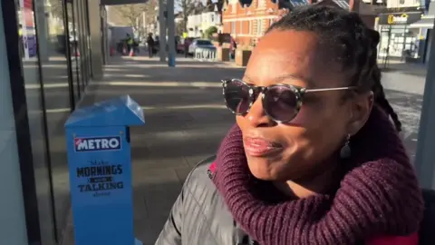 Christal Douglas, wearing sunglasses, speaking near West Ealing station.