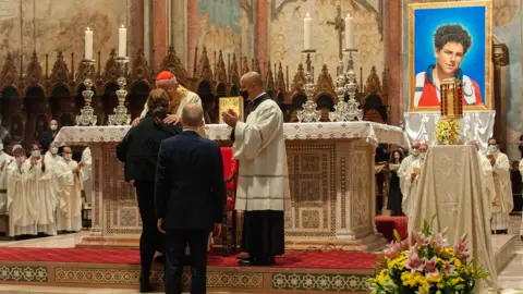 MASSIMILIANO MIGLIORATO/IPA MilestoneMedia/PA Cardinal Agostino Vallini greets the mother and father of Carlo Acutis as he celebrates Mass for the beatification process