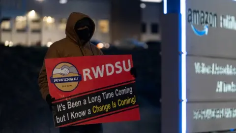 Getty Images man with RWDSU sign outside warehouse in Alabama