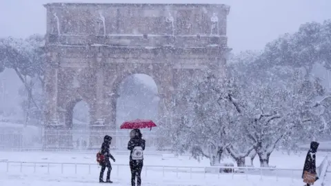 AFP Tourists visit the Arch of Constantine during a snowfall in Rome