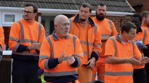 Alex Hannam Staff applaud as cortege goes past