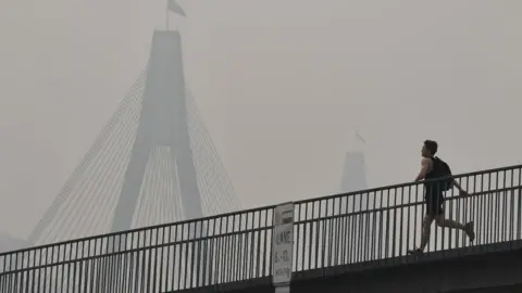 Getty Images A man runs over a bridge during a smoky haze in Sydney on Tuesday