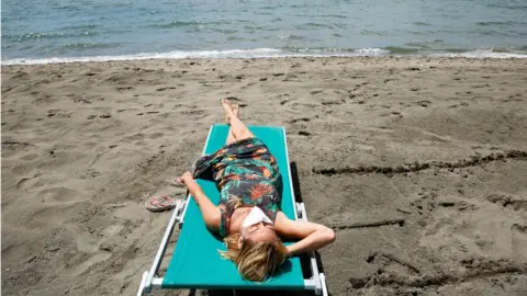 Reuters A woman wearing a face mask sunbathes at the beach after it officially reopened for the first time following the country"s strict coronavirus disease (COVID-19) lockdown, in Fregene, near Rome, Italy,