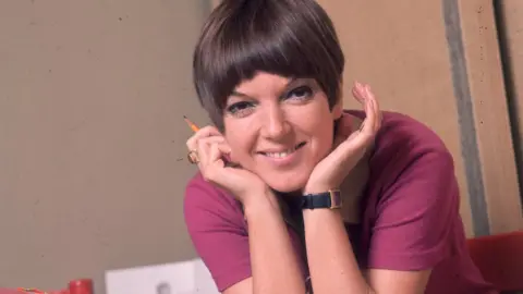 Getty Images circa 1965: British fashion designer Mary Quant resting her chin in her hands while taking a break from work