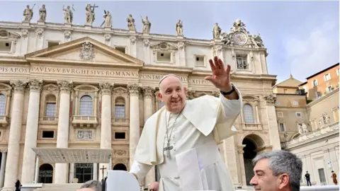 EPA Pope Francis with hand up in front of Vatican building