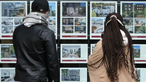 Getty Images People looking at property adverts in an estate agent's window