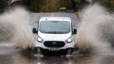 Getty Images A white van drives through water after heavy rain in November 2023