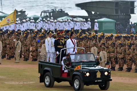 AFP Sri Lankan President Mahinda Rajapakse (C) rides in a jeep during a Victory Day parade in Colombo on May 18, 2013.