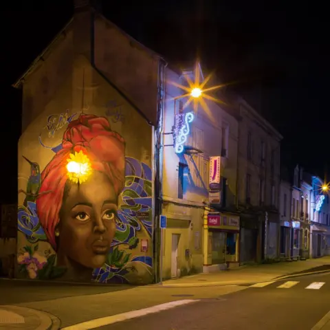 Claire Spreadbury A street light illuminates a mural of a woman's face