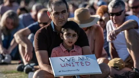 Getty Images A young boy holds a placard as he takes part in a vigil to remember the victims of the Christchurch mosque attacks, on March 24