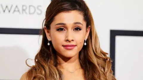 Reuters A photo of Ariana Grande from the shoulders up, she's at some kind of awards ceremony smiling into the camera.