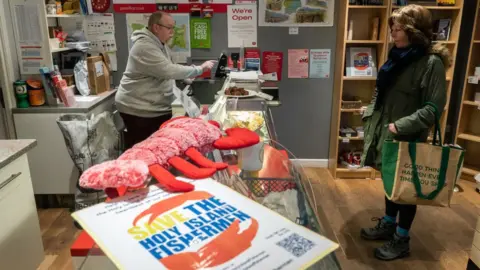 Getty Images A "Save the Holy Island Fishermen" leaflet in the post office on Lindisfarne