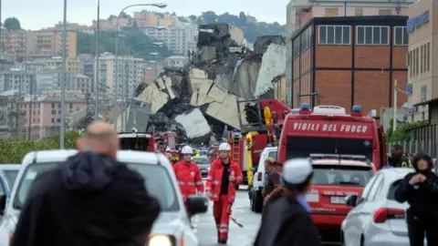 AFP Large mound of debris is shown blocking a road, surrounded by emergency services