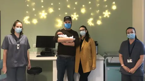 Aneurin Bevan University Health Board Parents Helen Jewell and Tom Brooks with Poppy along with the midwives that helped deliver her, Frankie and Zoe.