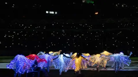 Rafalia Henitsoa/Getty Images Dancers getting on stage covered in multicoloured lights, 25 August